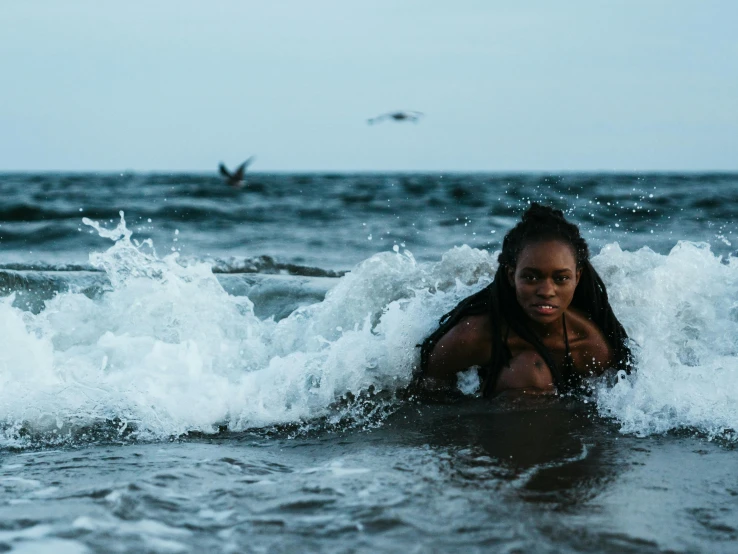 a girl is swimming in the ocean with a bird above her