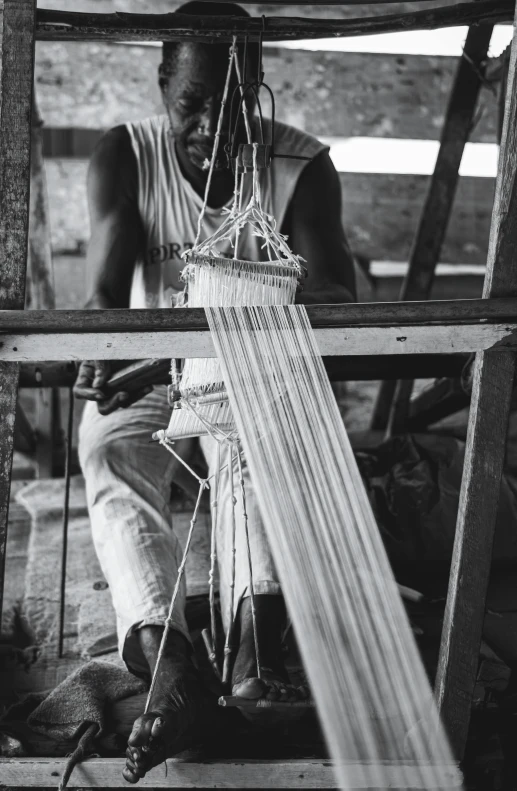 the man is weaving things on a bamboo frame