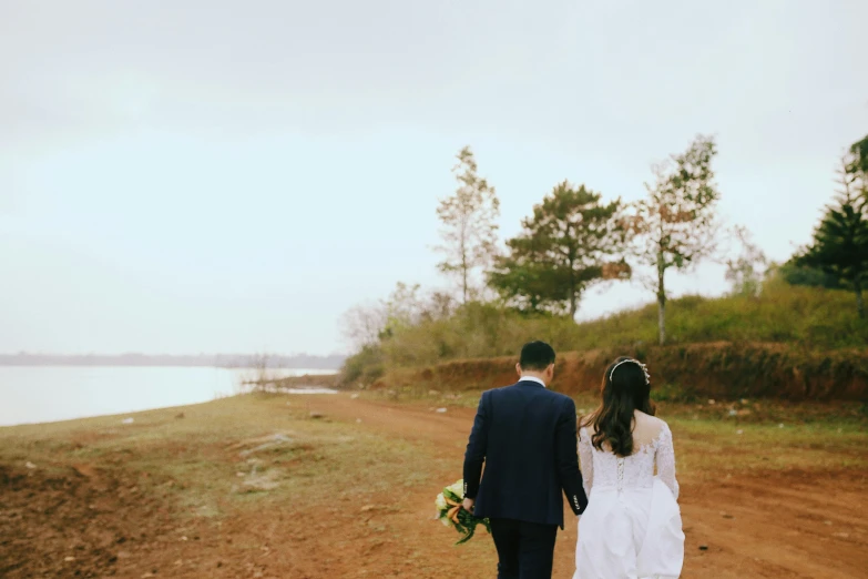 the couple are walking along the dirt road