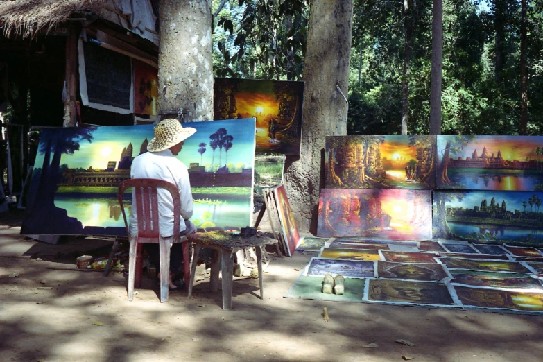 a man sits and looks at paintings on display