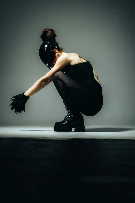 a person squatting down in kneels against a gray background