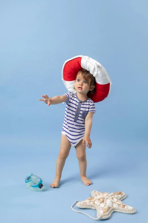 the baby in the striped romper is throwing the red and white life vest