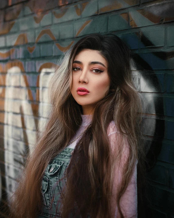 young woman standing against graffiti wall in street with long hair