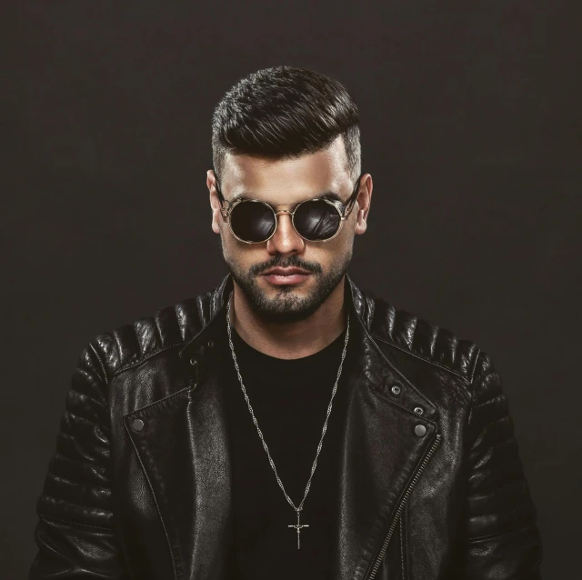 a man wearing sunglasses stands in front of a black background