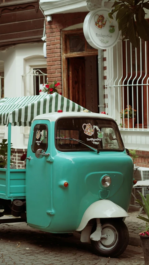 a small turquoise truck sits parked in front of a building