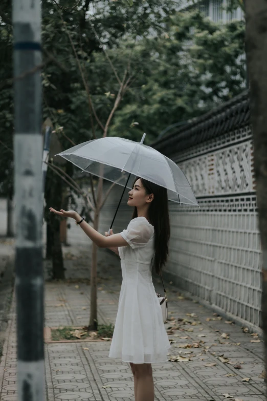 a woman in a short white dress holds an umbrella up