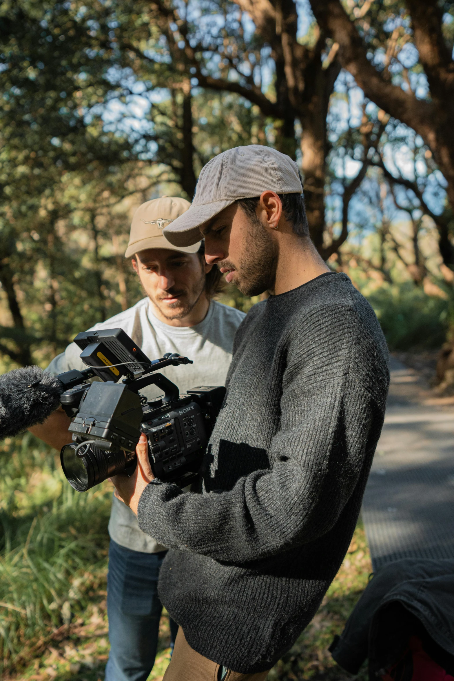 two men standing outside while they are recording some people