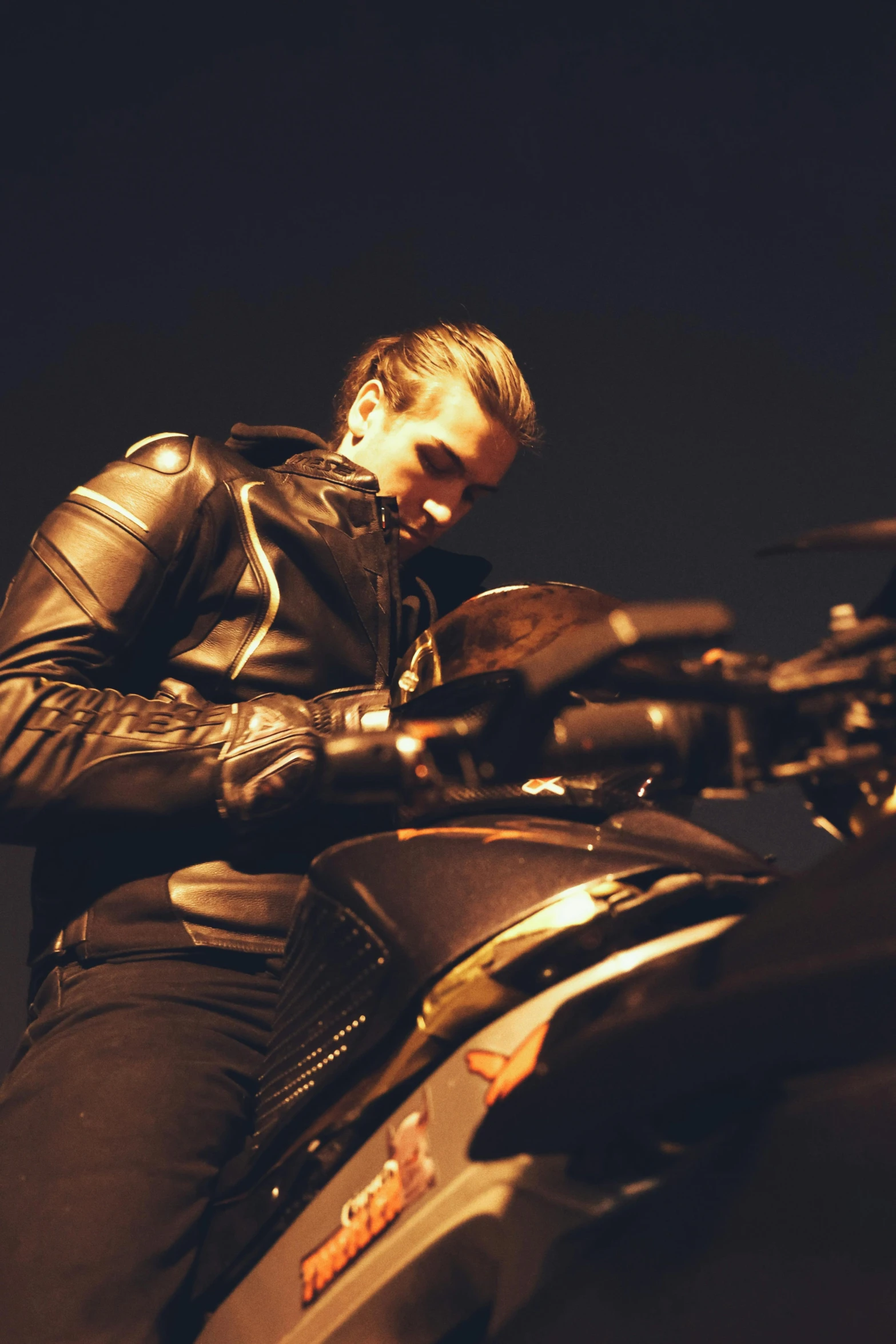 a man in black leather outfit leaning on a motor cycle