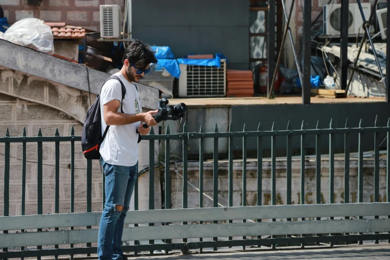 a man stands on his skateboard holding a camera