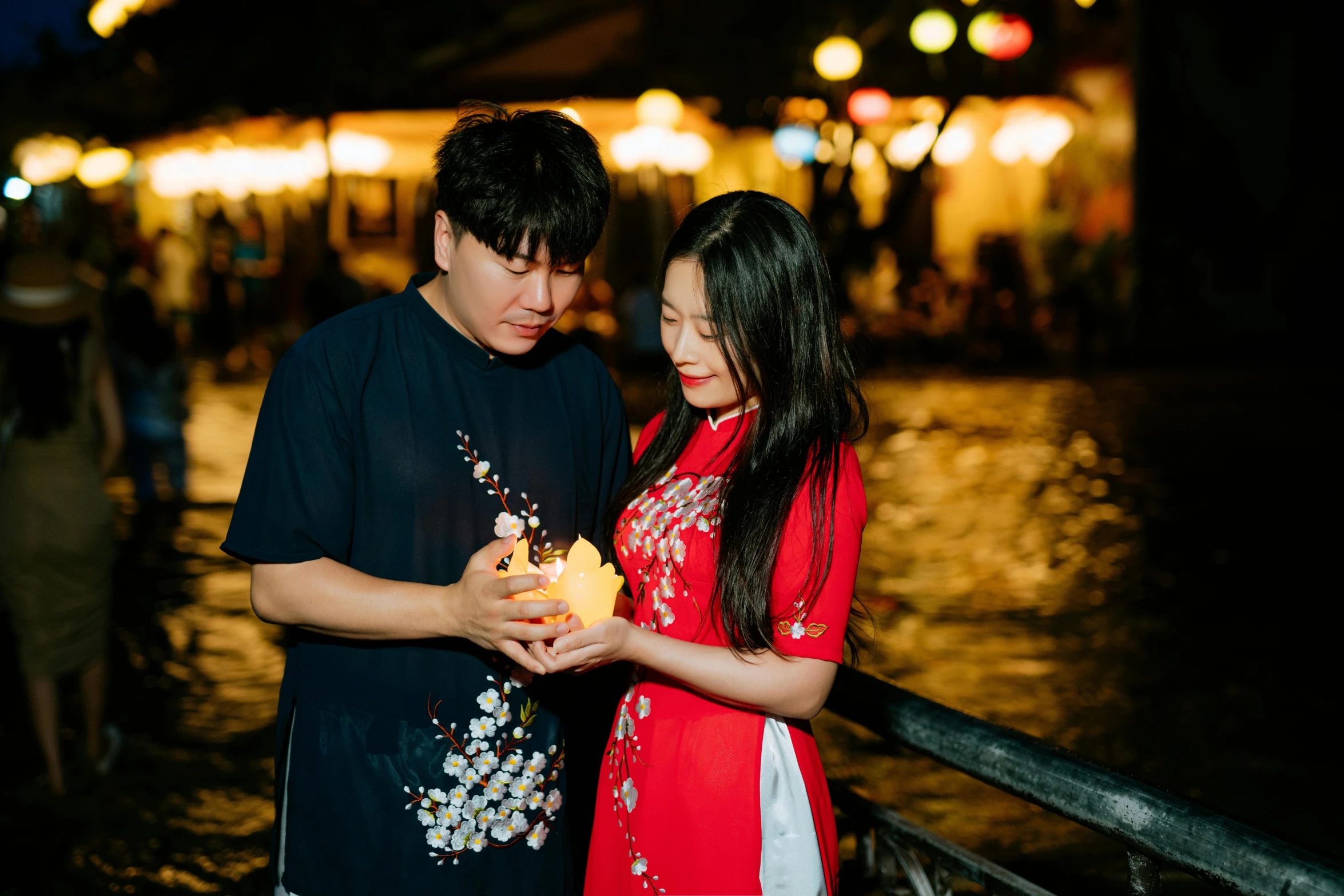 a man and woman pose for a po near a walkway at night