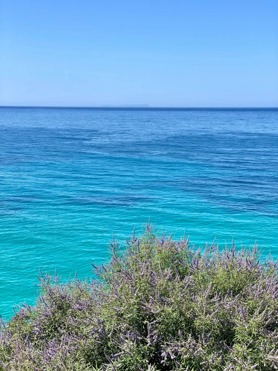 the ocean and boat are seen from the top of a hill