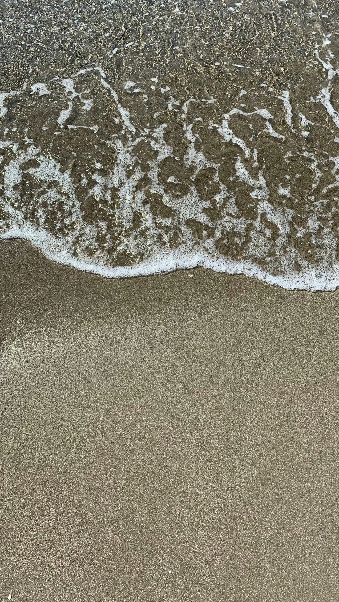 a sandy beach with a wave crashing on it