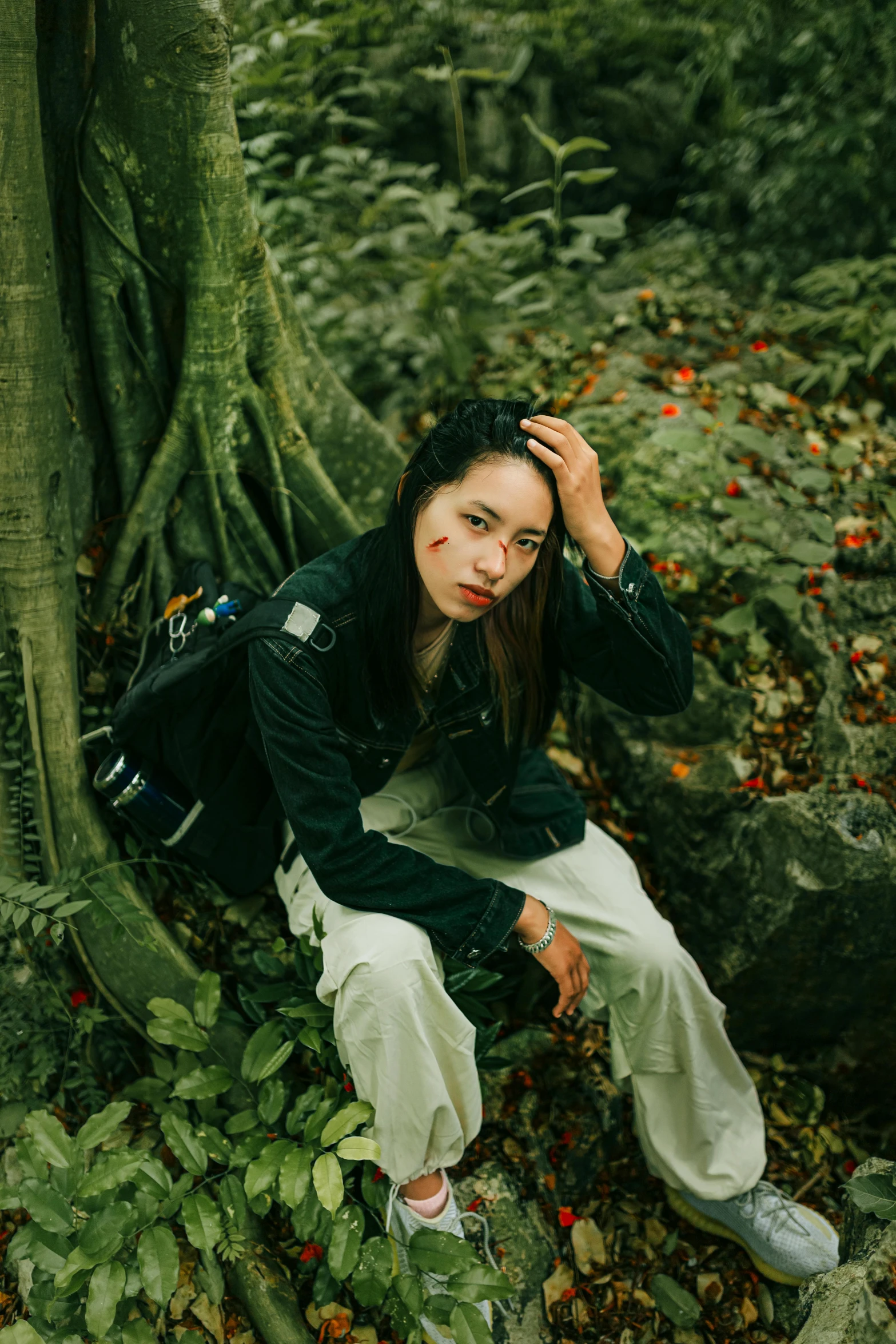 a young woman sitting on the ground near a tree