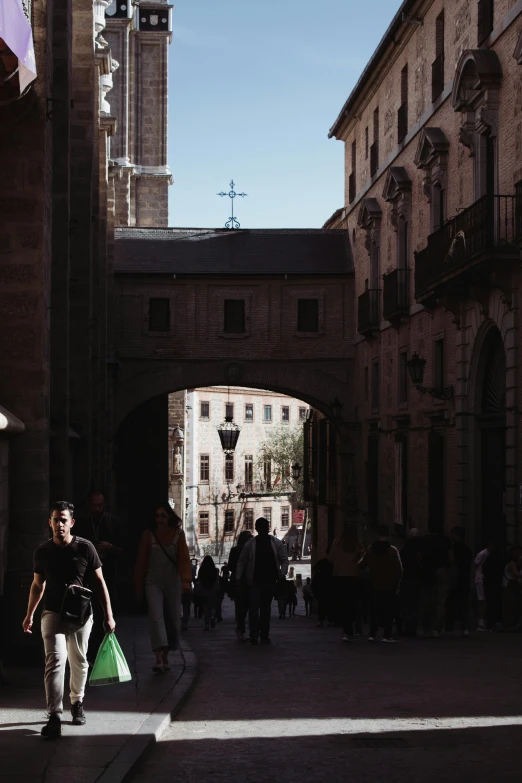 people walking through an open stone street under the clock tower