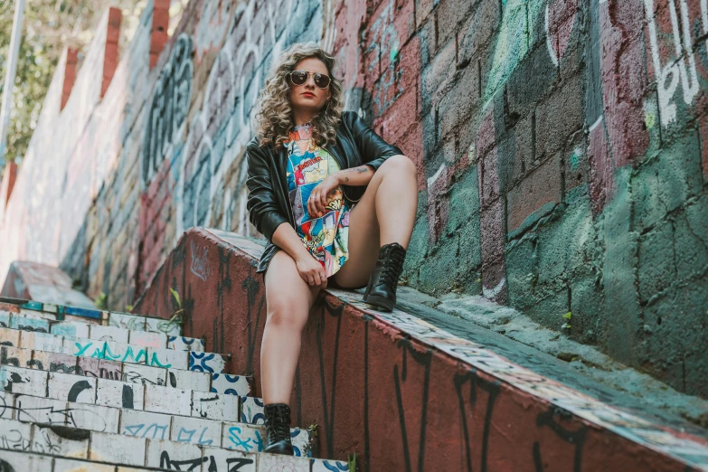 woman in sunglasses sits on concrete step and looks off into distance