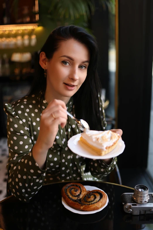 a woman holds a fork to slice her pastry