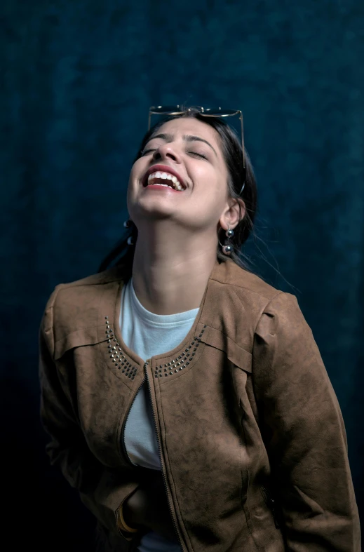 a woman laughing with her eyes closed wearing glasses