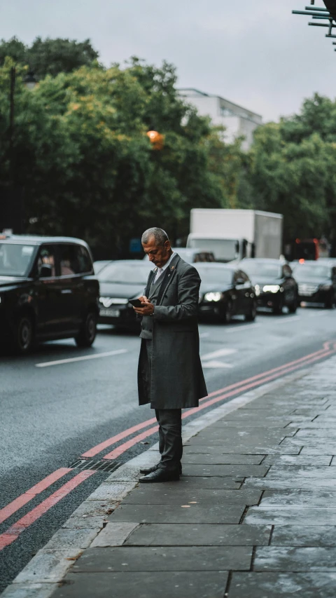 a man in coat standing on the side of a street