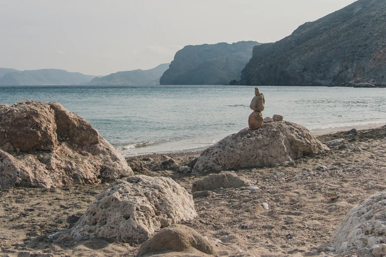 two rocks by a body of water with mountains in the background