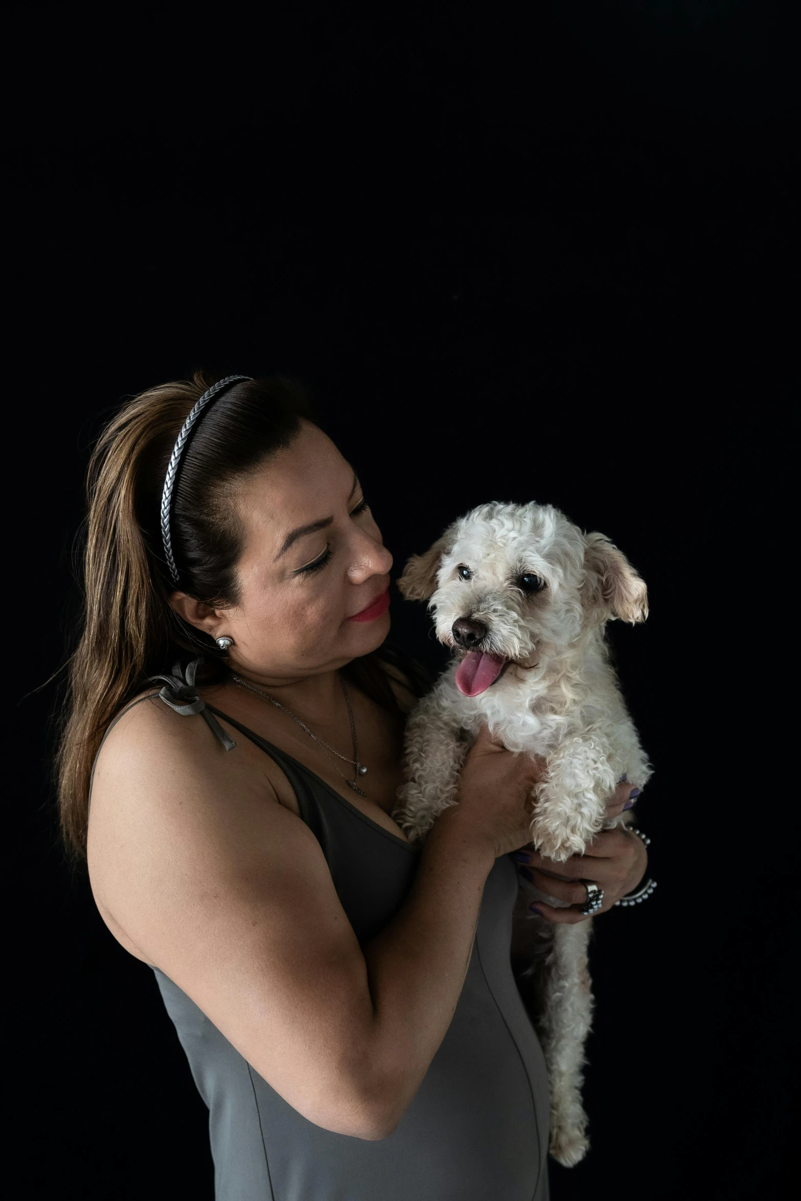 a woman with a small white dog with a tennis racket in her hand