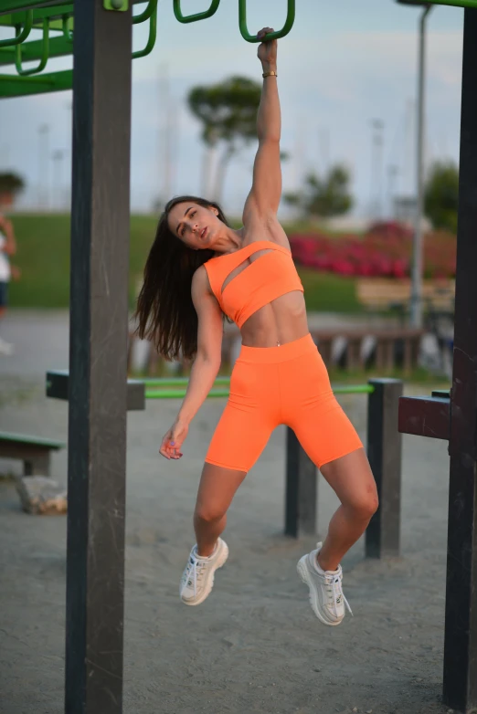 a female in an orange sport suit is working out on a bar