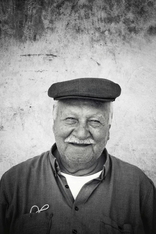 an older man with a mustache and hat in front of a wall