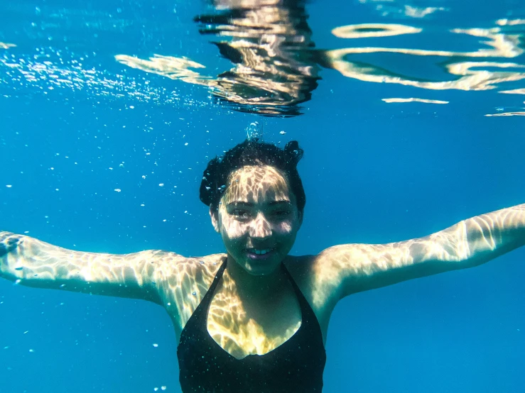 a woman swimming underwater under water with a black top