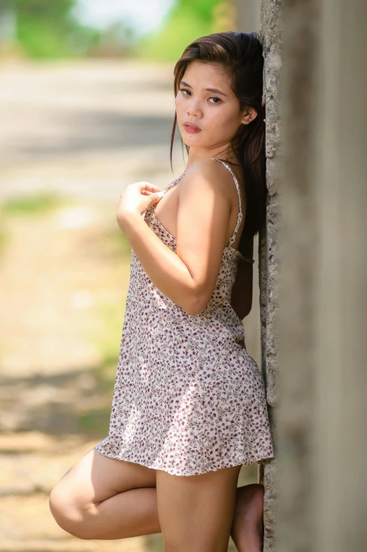 a girl posing near a wall with her hand on her hip