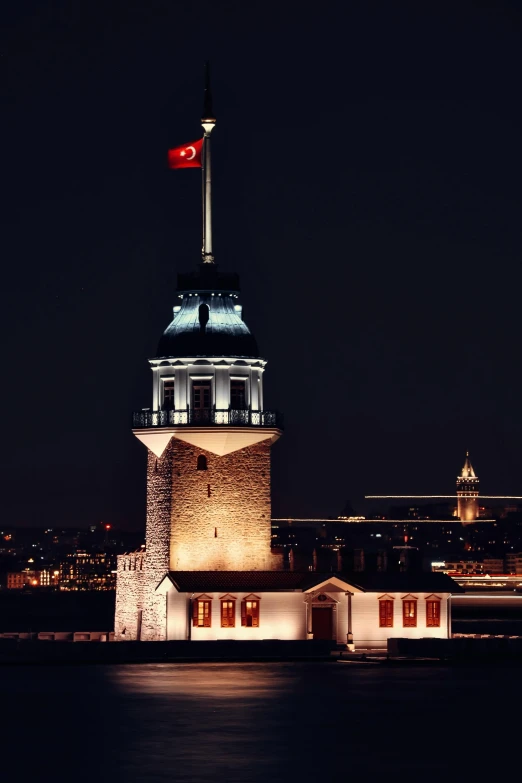 a clock tower lit up at night with the moon in the sky