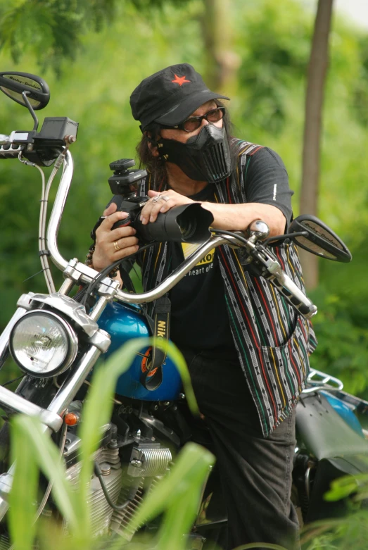 a man sitting on a motorcycle that is parked near some trees