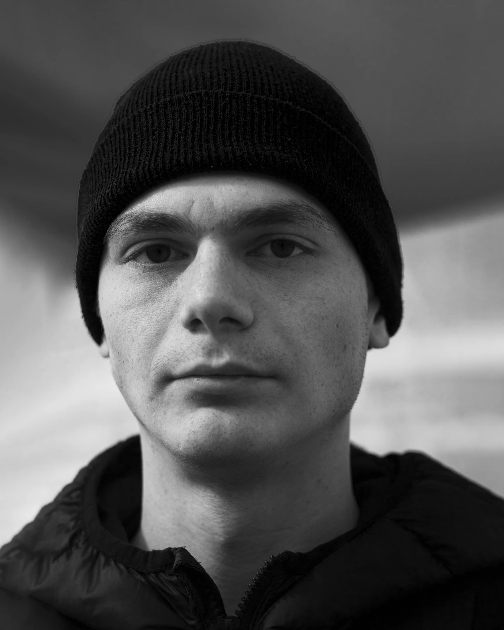 a black and white po of a young man in a black coat and beanie