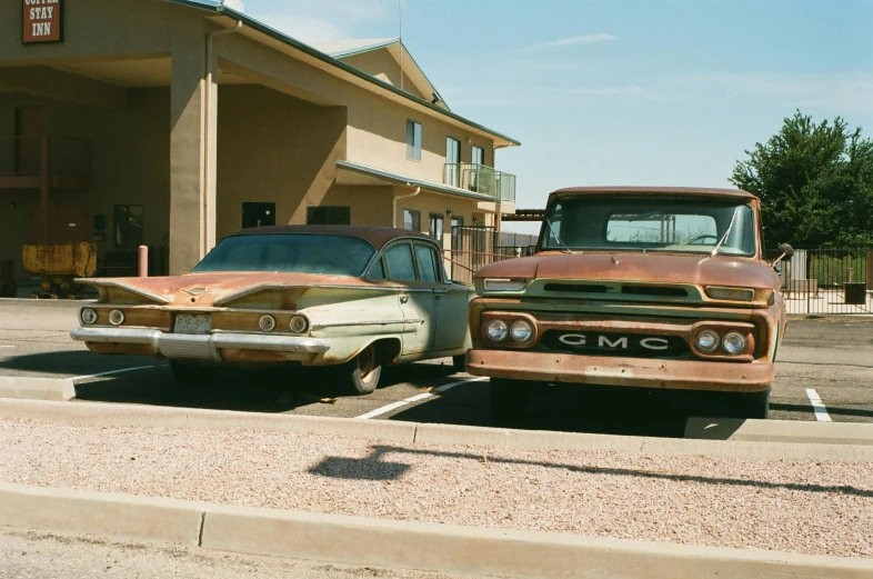 two old cars in parking lot with motel sign in background