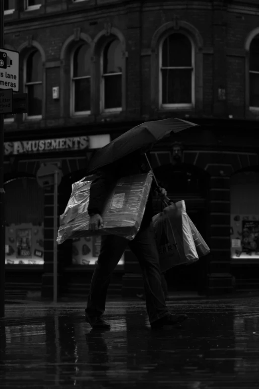 black and white pograph of man walking down street with umbrella