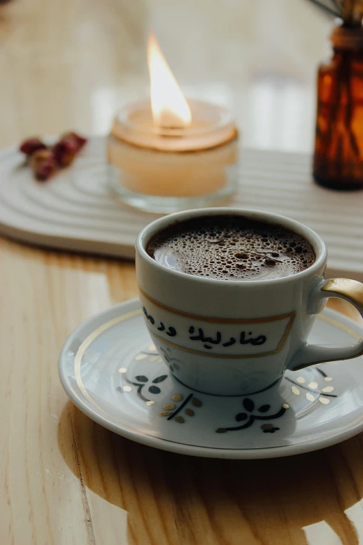 a small cup of cappuccino on a saucer with the candle on the side