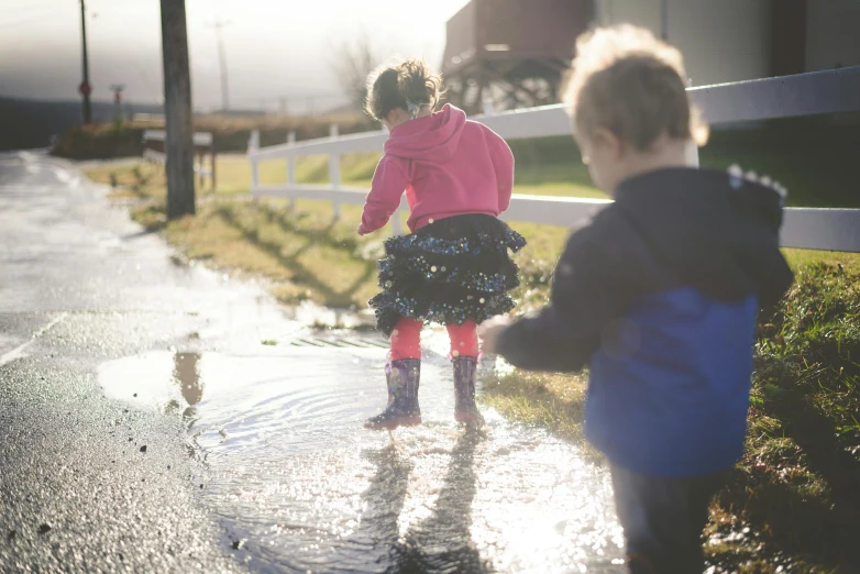 two small children playing in a dle on a road