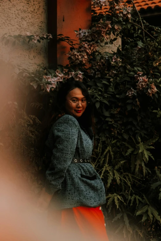 an attractive woman standing in front of a bush