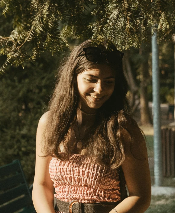 a girl standing under a tree holding a cell phone