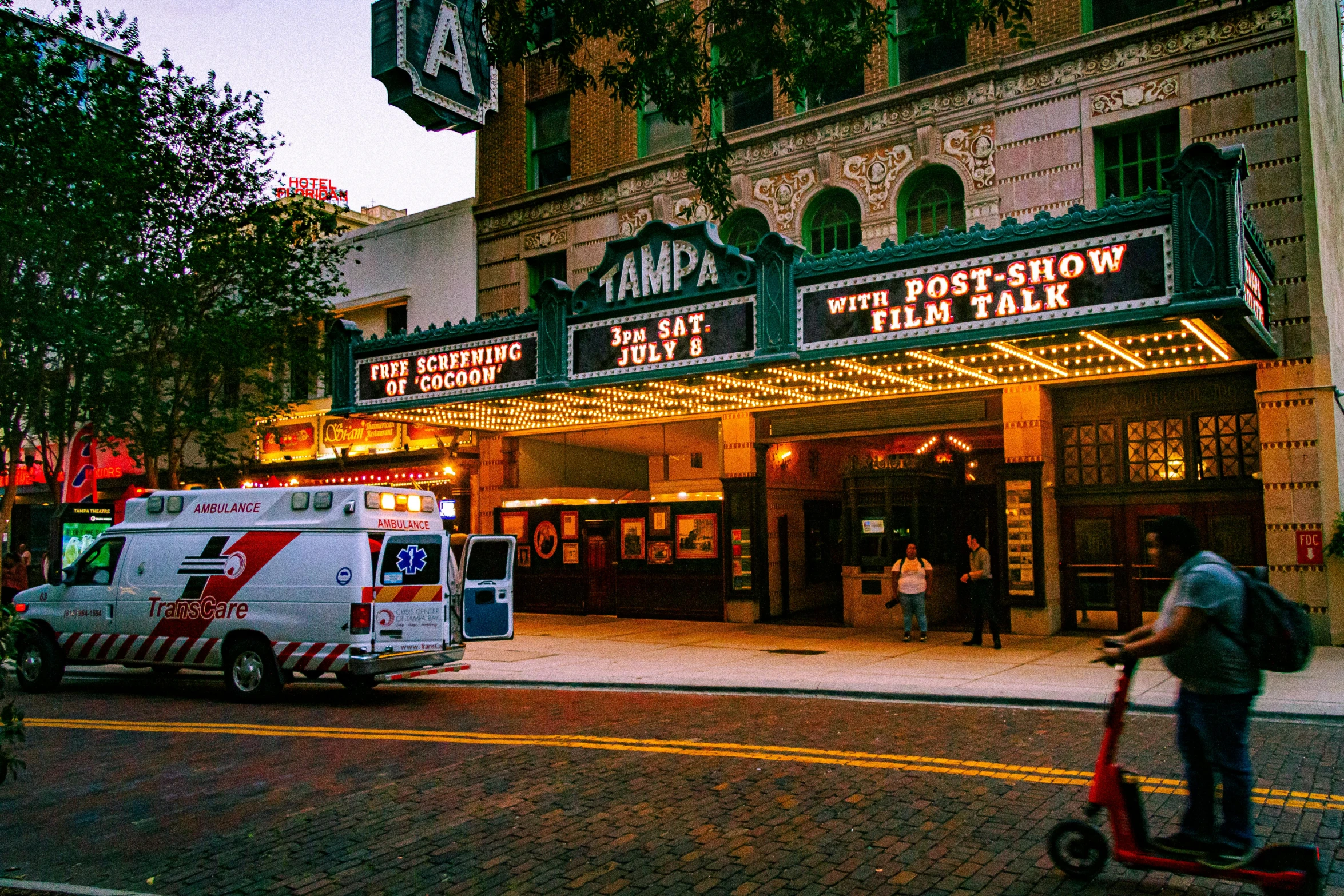 a person riding a scooter near a movie theater