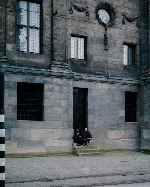 two people sitting on the steps of a building