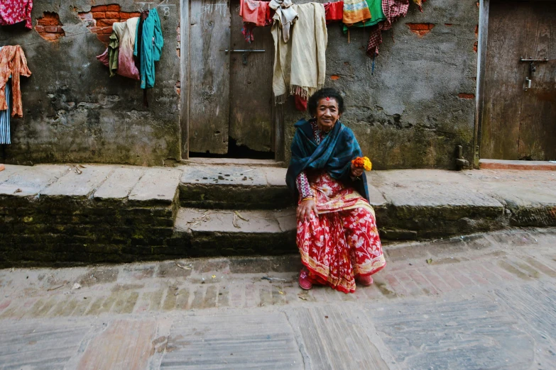 woman wearing colorful clothing sitting in front of stone steps