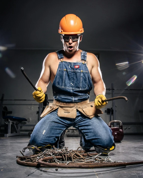 a man in a hard hat is sitting on the floor wearing an orange helmet and gloves