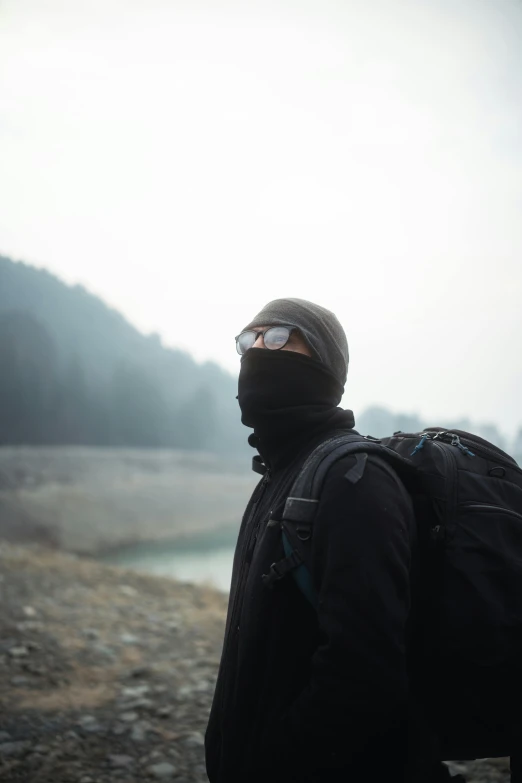 man in winter clothing, with hiking gear standing on a rocky field