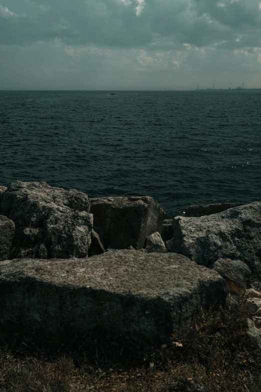 a bench that is by some water under a cloudy sky