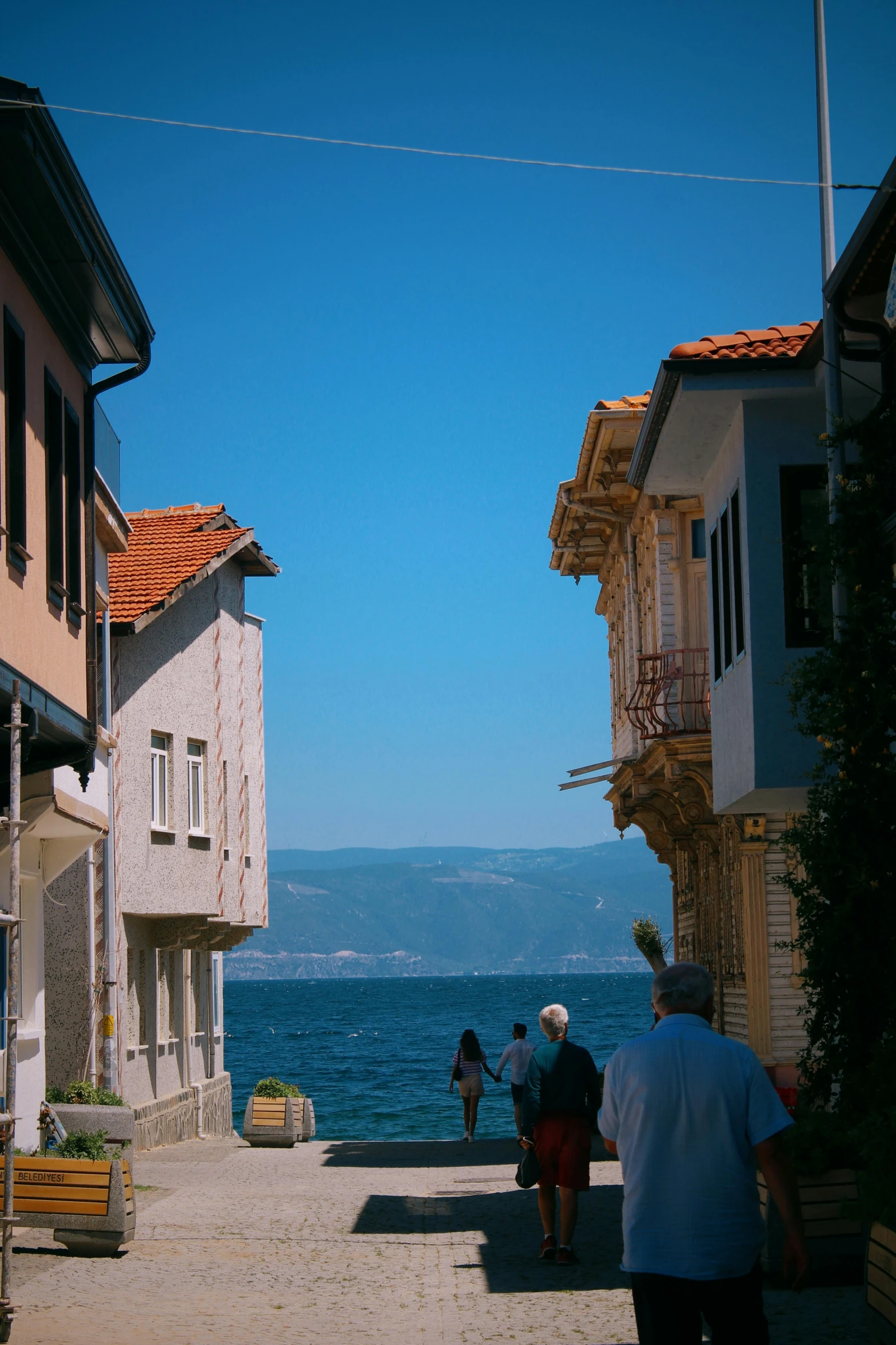 people walking down an alley beside the water