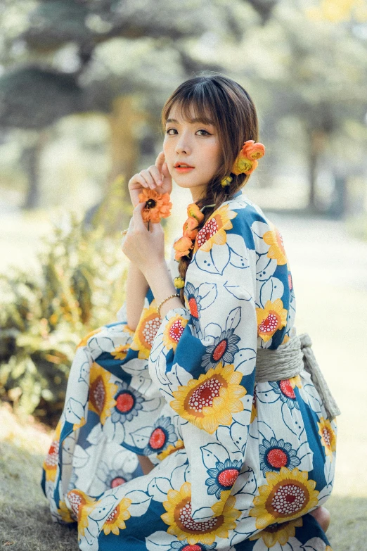 a woman in a sunflower dress sitting on a tree trunk