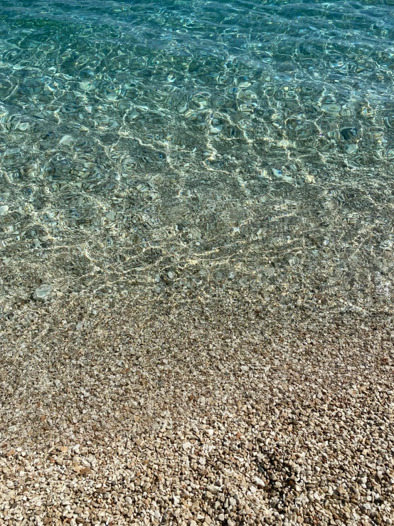 water and sand at the beach with a boat in the background