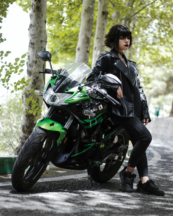 young lady wearing black sitting on a green motorcycle