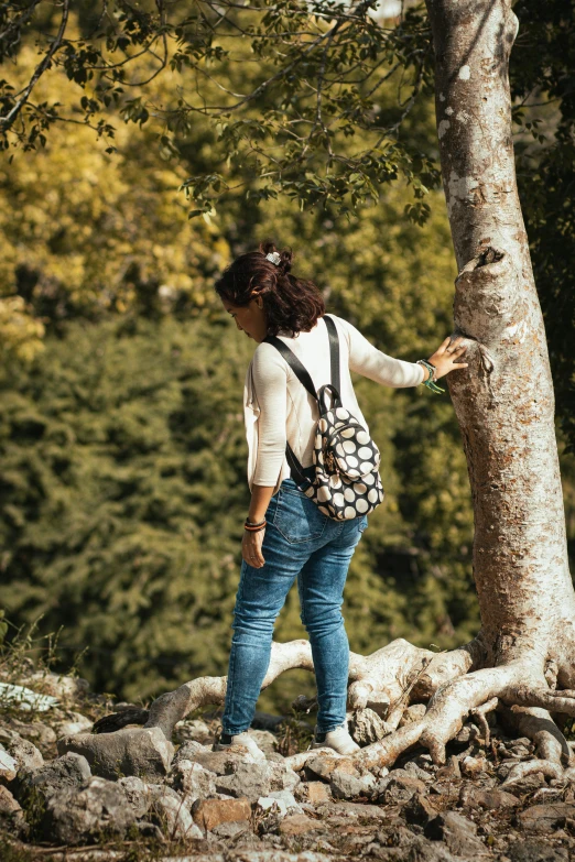 a woman standing next to a tree with lots of stones