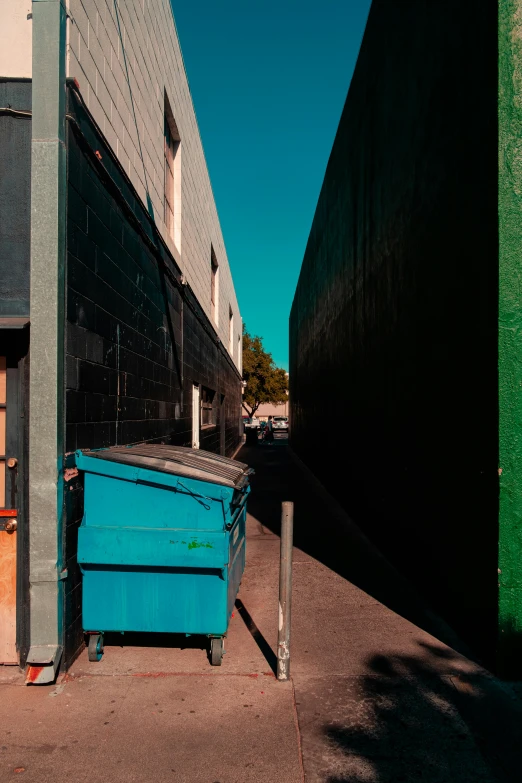 an empty blue dumpster sits in front of a building