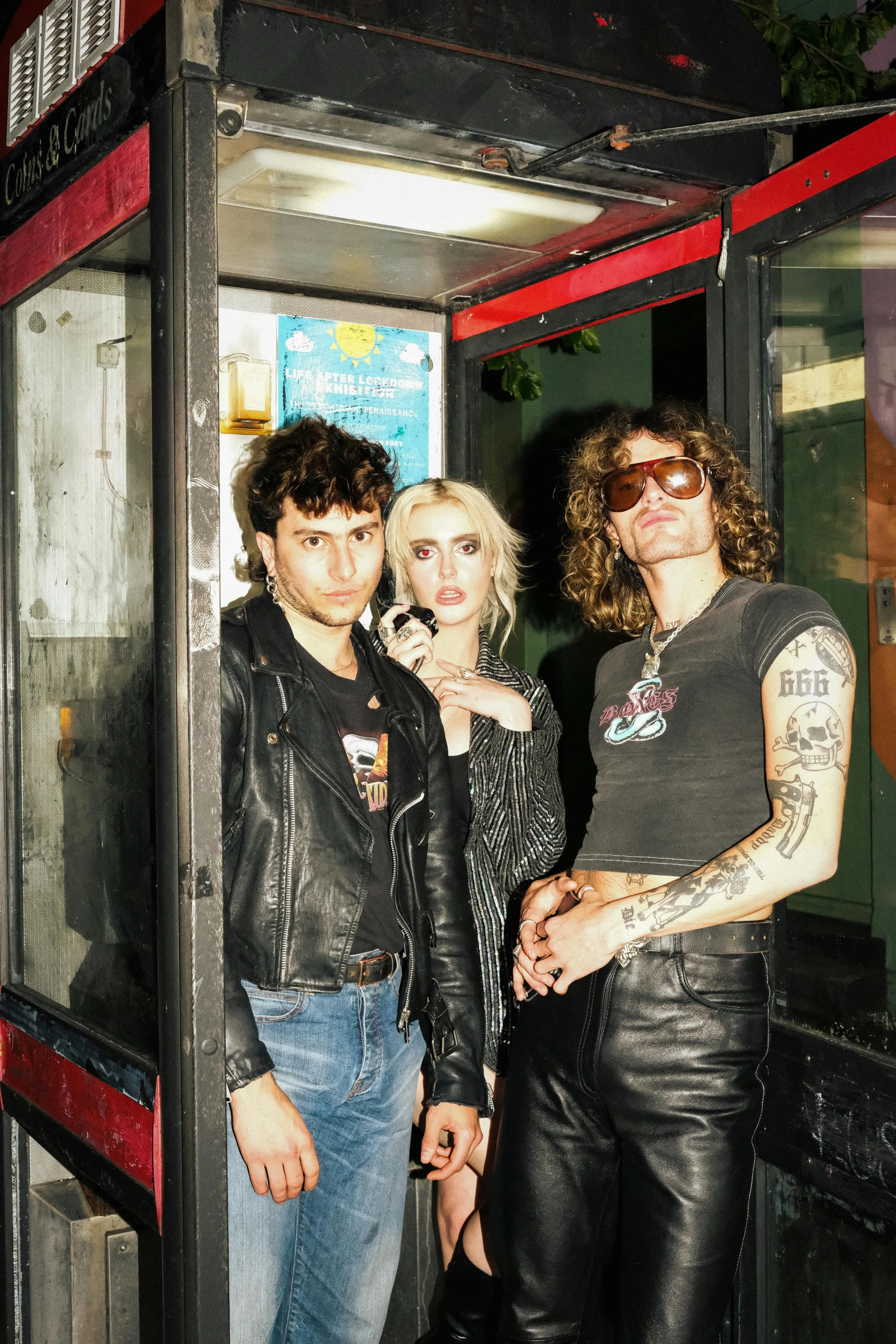 a group of young people pose next to a telephone booth